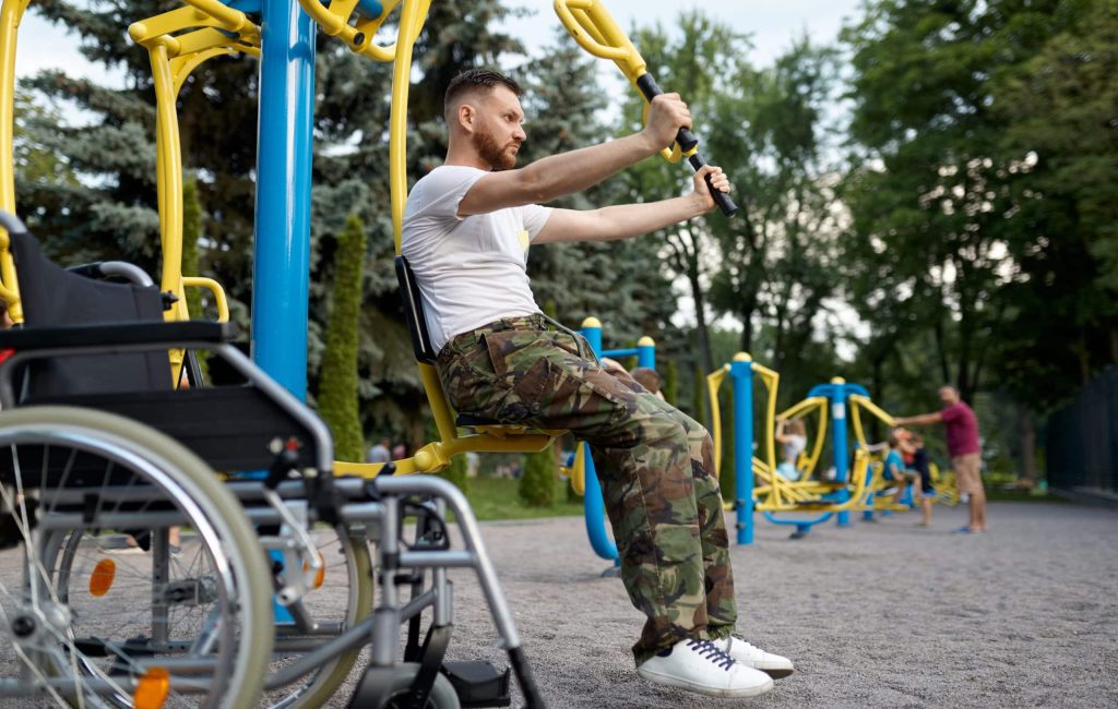 Disabled veteran, sport training in the park. Paralyzed people and disability difficulties, handicap overcoming. Handicapped male person on sport ground